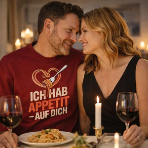 Paar bei romantischem Dinner trägt rotes Meatware Premium Organic Sweatshirt mit Spaghetti-Herz-Motiv und Schriftzug „Ich hab Appetit auf Dich“ – Liebesdesign zum Thema Liebe geht durch den Magen