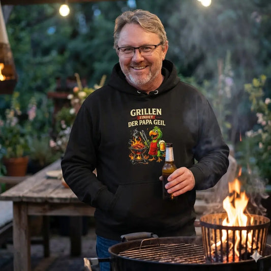 Vater im gemütlichen Meatware Grill-Papagei Hoodie am abendlichen Feuer im Garten.