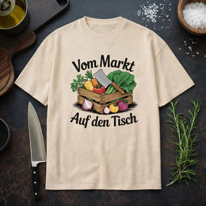 Oversized T-Shirt in Beige mit Motiv „Vom Markt auf den Tisch“ – rustikales Food-Design von Meatware, flaches Küchen-Mockup mit Messer, Kräutern und Zutaten