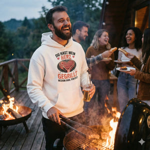 Lachender Mann am Grill in beigem Oversized Hoodie mit Steak-Herz-Motiv "Du hast mein Herz gegrillt", BBQ-Vibe