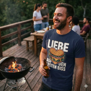 Glücklicher Mann mit Burger in der Hand trägt marineblaues T-Shirt mit Burger-Herz-Motiv "Liebe auf den ersten Biss", BBQ-Party