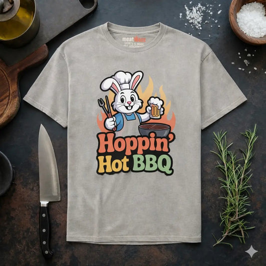 Graues Meatware Premium T-Shirt mit Hoppin Hot BBQ Grillhasen Design und Meatware Nackenbranding im BBQ Küchen Flatlay Mockup mit Messer und Rosmarin