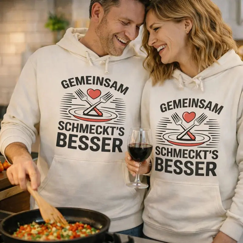 Paar trägt Meatware Premium Hoodie ›Gemeinsam schmeckt’s besser‹ in heller Küche – liebevolles Design zum Thema Liebe geht durch den Magen