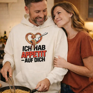 Paar in gemütlicher Küche trägt hellen Meatware Oversized Hoodie mit Spaghetti-Herz-Motiv und Schriftzug „Ich hab Appetit auf Dich“ – humorvolles Liebesdesign, Liebe geht durch den Magen