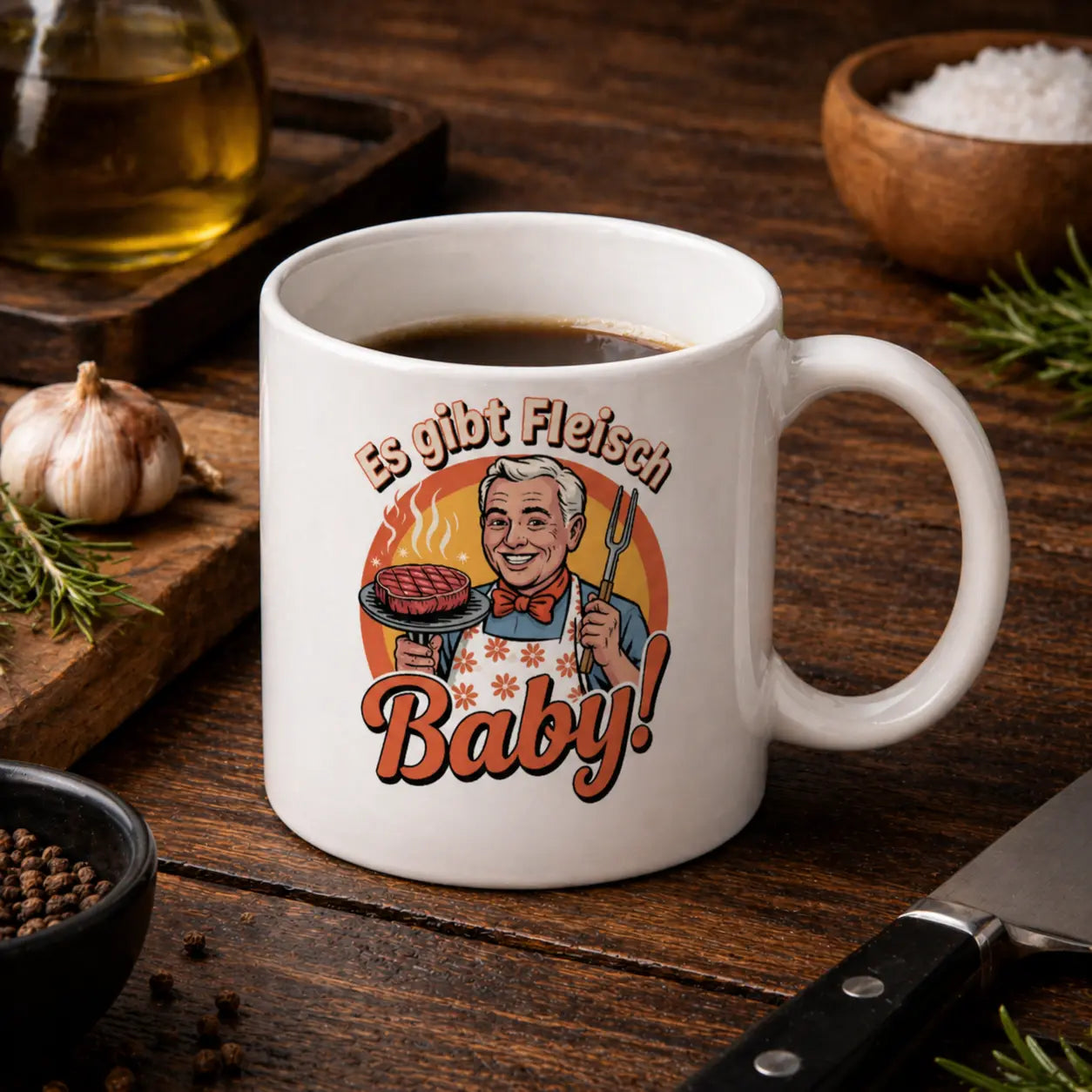 Weiße Keramiktasse mit Retro Grill Design „Es gibt Fleisch Baby“ in Nahaufnahme auf Holztisch, Meatware Tasse mit Steak Motiv und Grillmeister Illustration