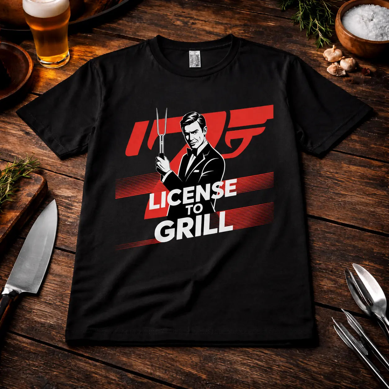Meatware License to Grill BBQ T-Shirt mit Agenten-Design und Grillgabel auf schwarzem Shirt, präsentiert in rustikalem BBQ-Mockup mit Bier, Kräutern, Knoblauch und Grillbesteck auf dunklem Holztisch.