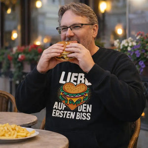 Schwarzes Meatware Premium Organic Sweatshirt mit Burger-Herz Motiv und Schriftzug „Liebe auf den ersten Biss