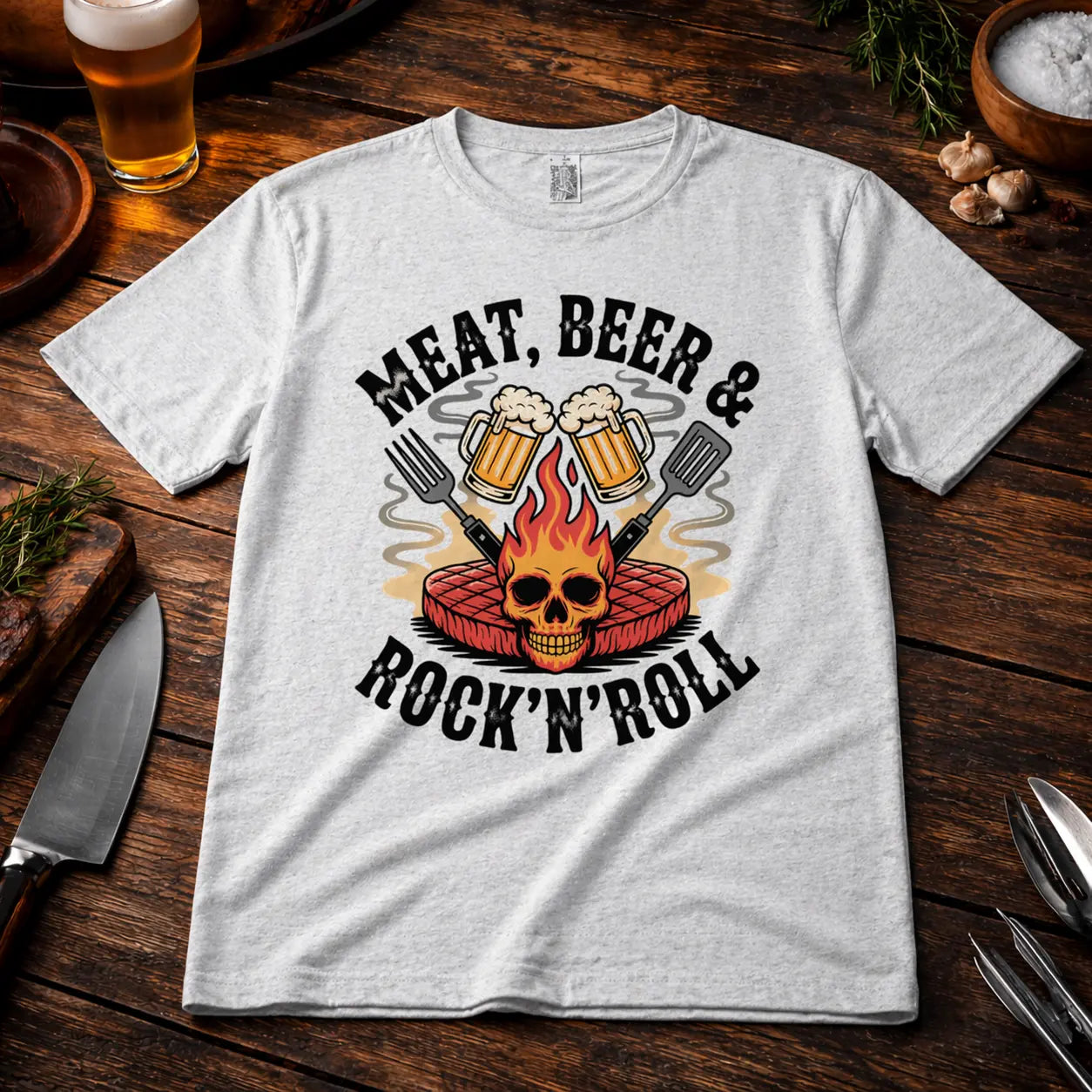 Premium T-Shirt grau mit Meat Beer Rock’n’Roll Grillmotiv auf Holz BBQ Mockup mit Bier, Grillbesteck und rustikaler Küche Szene für Herren