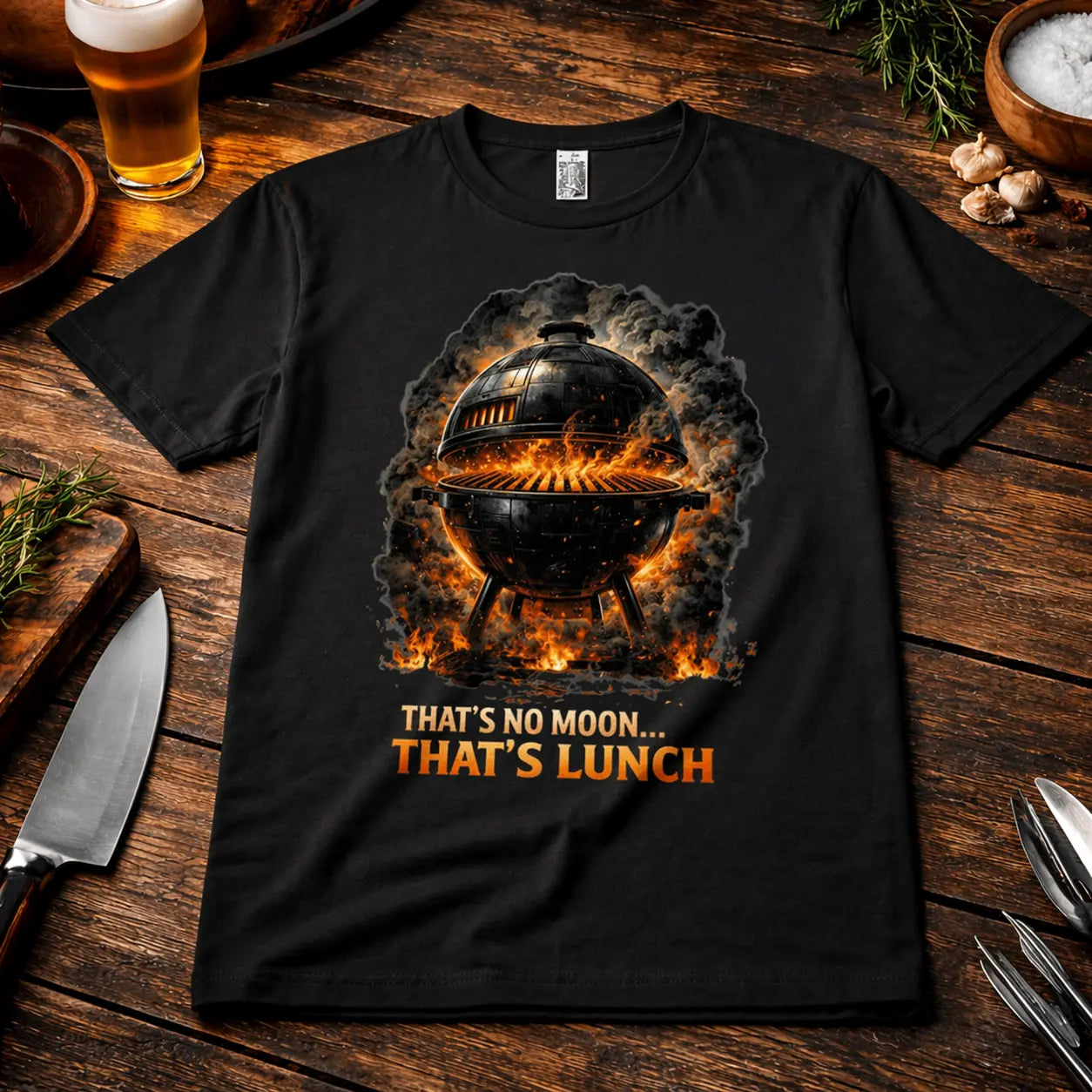 Schwarzes Premium T-Shirt mit BBQ Grill Motiv „That’s No Moon That’s Lunch“ im rustikalen Grill Mockup mit Bier, Gewürzen und Küchenutensilien auf Holztisch