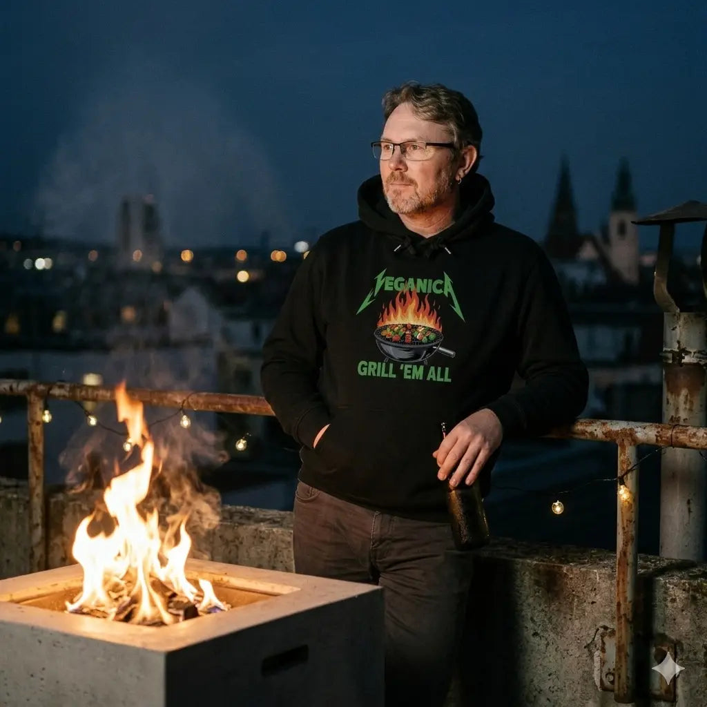 Mann im schweren Meatware Veganica Oversized Hoodie ohne Kordeln am nächtlichen Feuer.