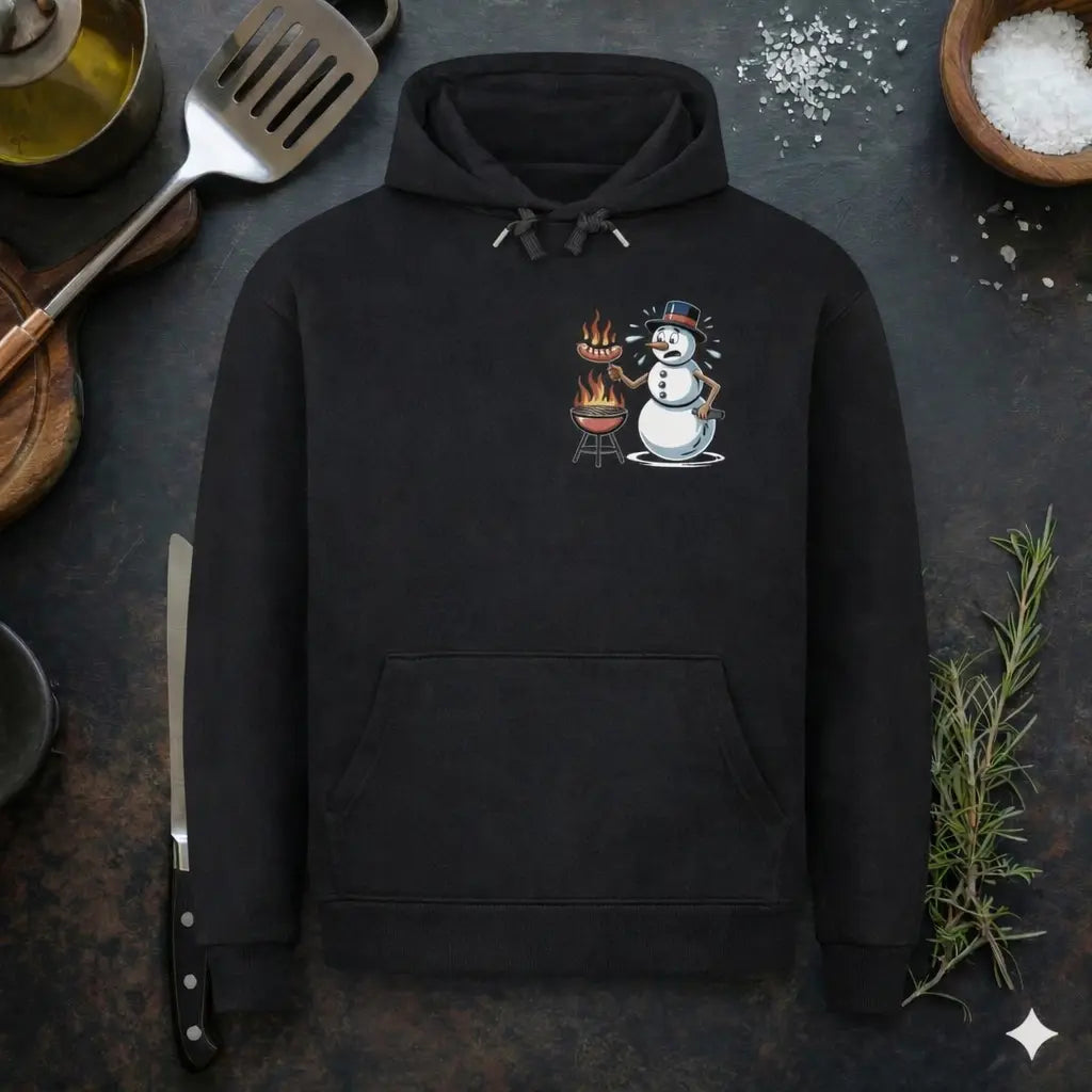 Schwarzer Hoodie mit lustigem Schneemann Grill Design „Für den Job brenne ich“, BBQ Humor Motiv mit Grill und Würstchen, präsentiert in rustikalem Küchen-Flatlay Mockup mit Grillbesteck, Kräutern und Salz.