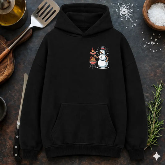 Schwarzer Oversized Hoodie mit lustigem Schneemann BBQ Grill Design „Für den Job brenne ich“, humorvolles Grillmotiv mit Würstchen und Flammen, präsentiert in rustikalem Küchen-Flatlay Mockup mit Grillbesteck, Messer, Salz und Rosmarin.