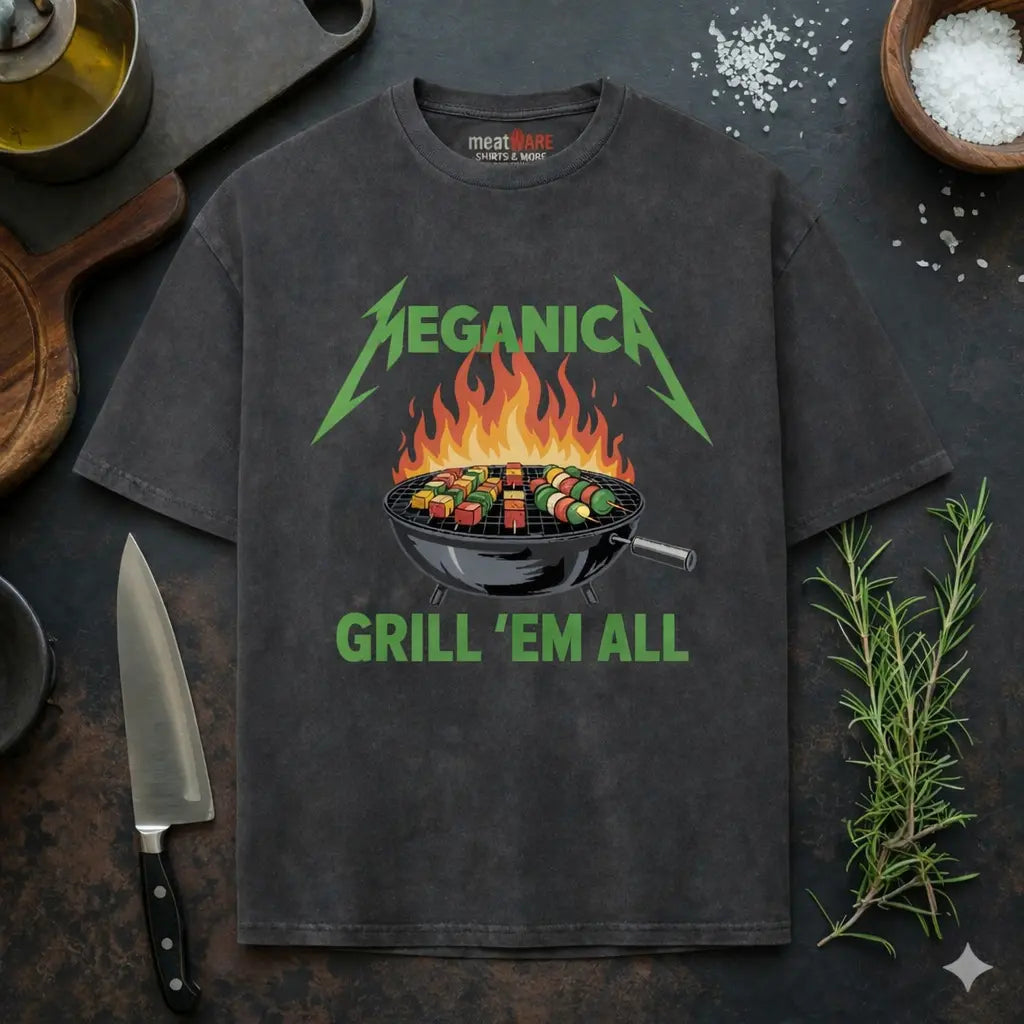 Dunkelgraues Meatware Oversized T-Shirt mit Veganica Grill ’Em All BBQ Gemüse Grill Design und Meatware Nackenbranding auf dunklem Küchen Hintergrund mit Messer, Rosmarin und grobem Salz